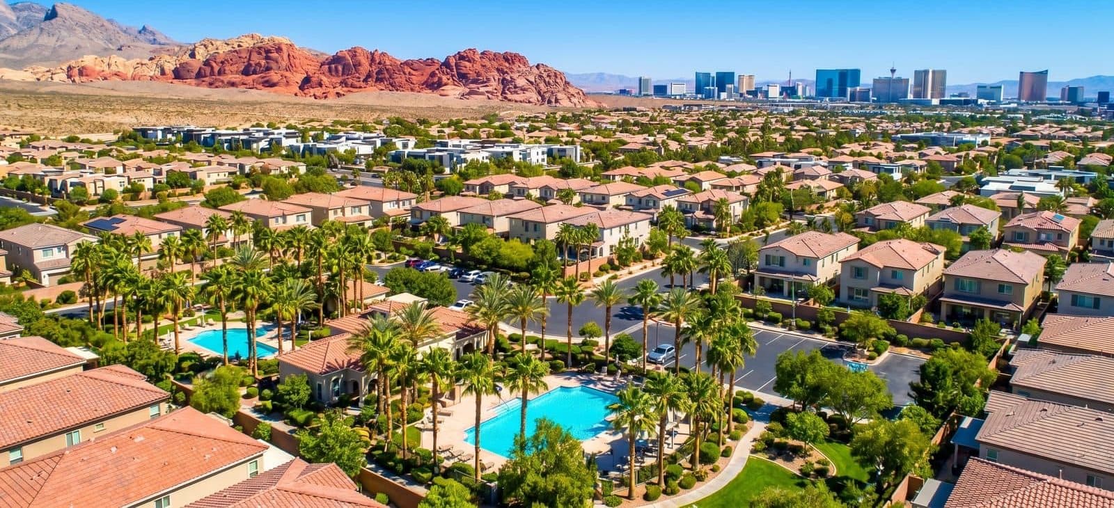 A Las Vegas master-planned neighborhood of homes with pools and palm trees, the Las Vegas Strip skyline and Red Rock Canyon on the horizon